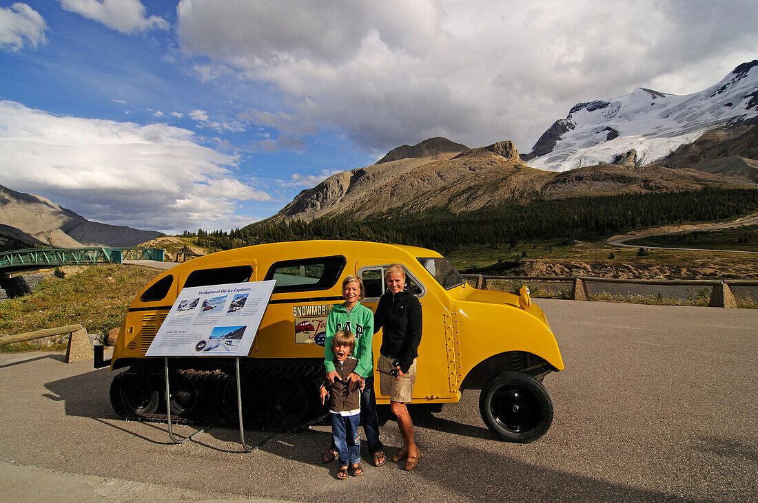 Family in front of a old snow mobile,  Icefields Parkway, Columbia Icefield, Jasper National Park, Alberta