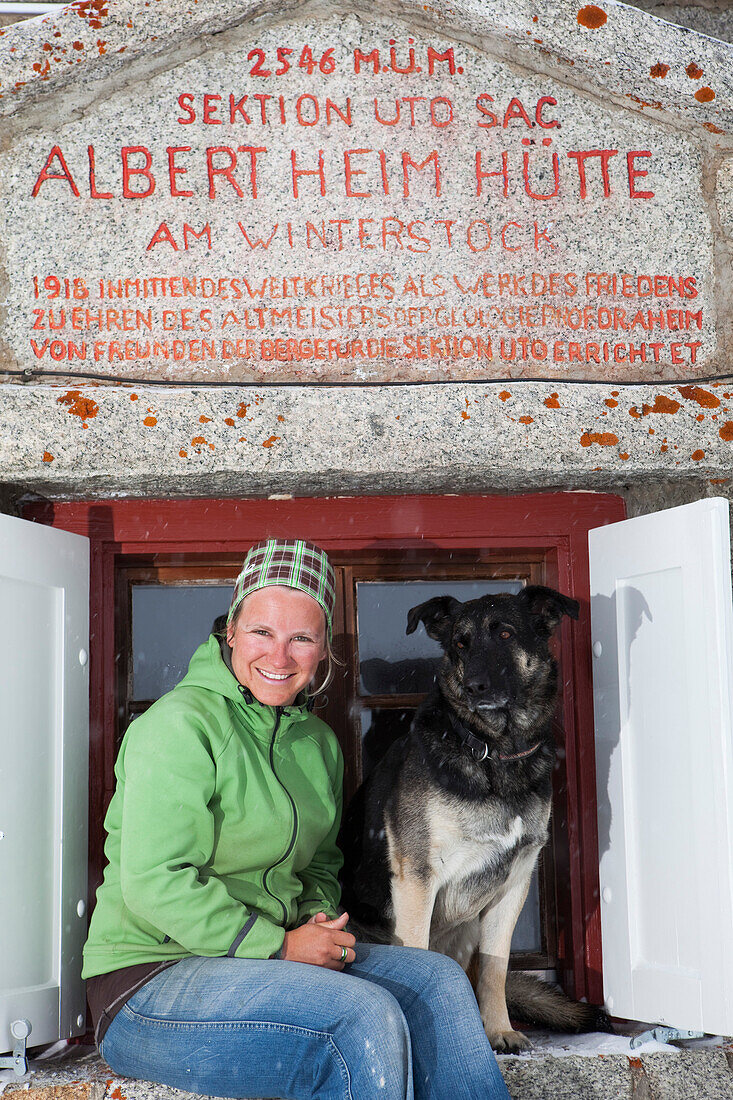 Woman and dog in front of a Albert Heim mountain lodge, Urner Alps, Canton of Uri, Switzerland