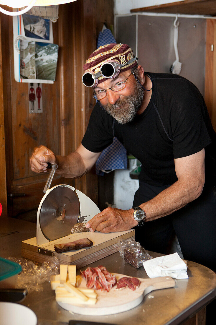 Man preparing snack in mountain lodge Cabane de l'A Neuve, Val Ferret, Canton of Valais, Switzerland