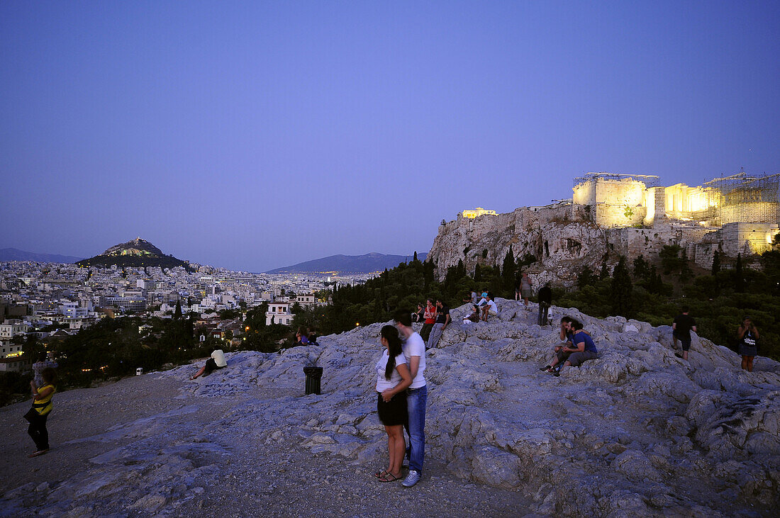 Menschen auf dem Areopag Felsen mit Blick auf Likavittos Hügel und Akropolis am Abend, Athen, Griechenland, Europa