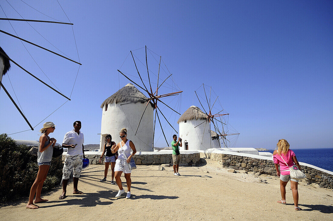 People and windmills at Venetia quarter under blue sky, island of Mykonos, the Cyclades, Greece, Europe