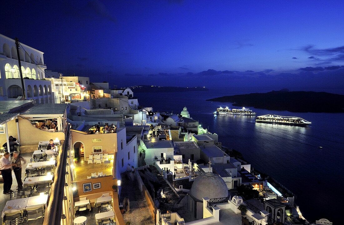 Häuser an der Küste und beleuchtete Fähren am Abend, Fira, Santorin, Kykladen, Griechenland, Europe