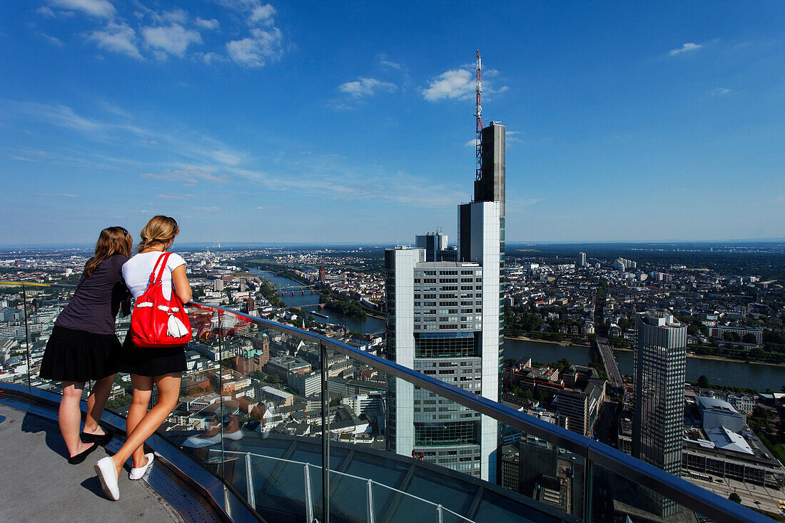 Two young women admiring the view towards the Commerzbank Tower, Frankfurt am Main, Hesse, Germany