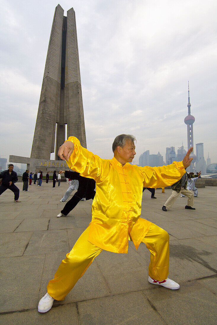 Chinese man practicing tai chi in the early morning in Huangpu Park with the Monument to the People´s Heroes in the background,  Shanghai,  China