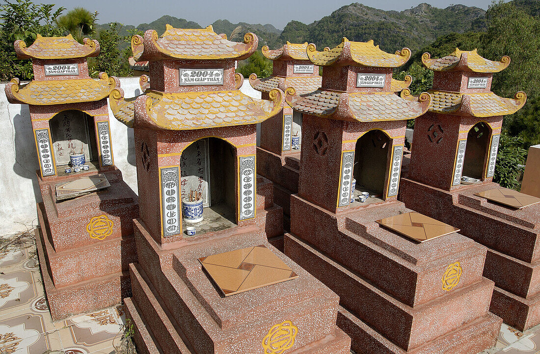 Family tombs in Cat Ba island cemetery,  Halong bay,  Vietnam. The cemetery is located next to a pagoda/temple on the top of a small mountain,  where villagers  go often to take care of their dead by lighting up incense sticks.