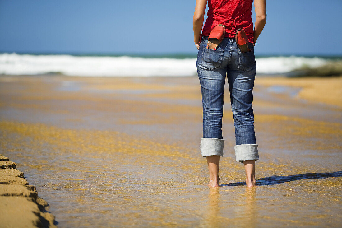 Portrait of a young woman with a pair of sandals on the beach