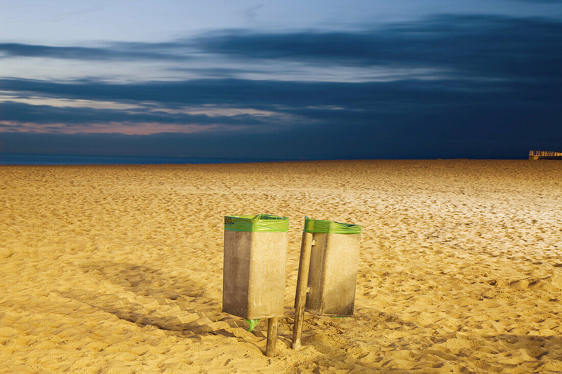 2 garbage cans,  at dusk on a beach on the North sea,  Belgium.