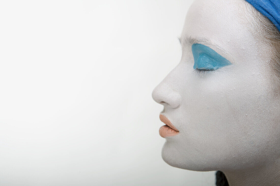Frau mit weißer Gesichtsschminke, blauen Augen und roten Lippen