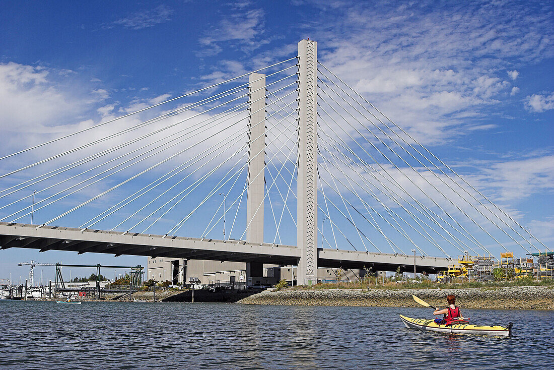 Woman sea kayaking by the Highway 509 bridge,  Tacoma,  Washington