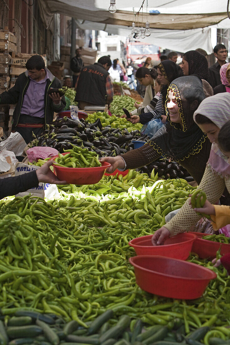 vegetable stall at a market in Tarlabasi, traditionally dressed women with headscarfs, mounds of produce, Istanbul, Turkey