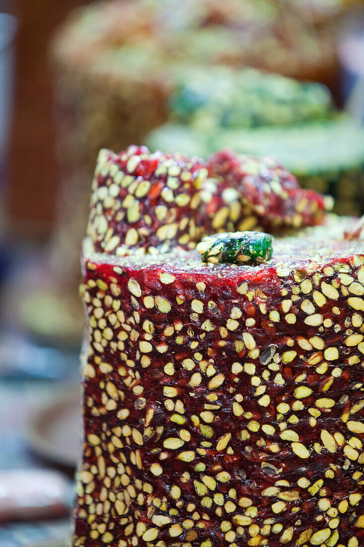Süßigkeiten, Verkauf, mit einem großen Messer wird ein Stück von der Turmform abgeschnitten, Türkischer Honig, Halva mit Pistazien, Istanbul