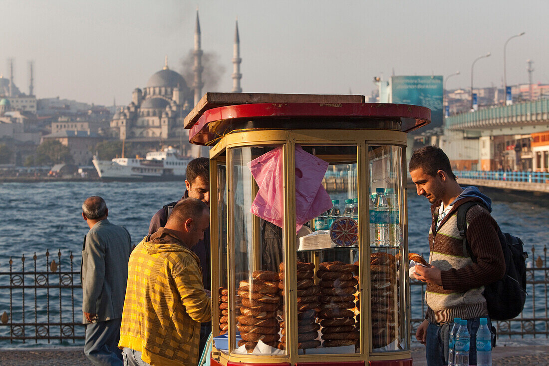 Menschen kaufen Sesamgebäck an einem Kiosk, Goldenes Horn, Galata Brücke, im Hintergrund die Neue Moschee, Istanbul, Türkei, Europa
