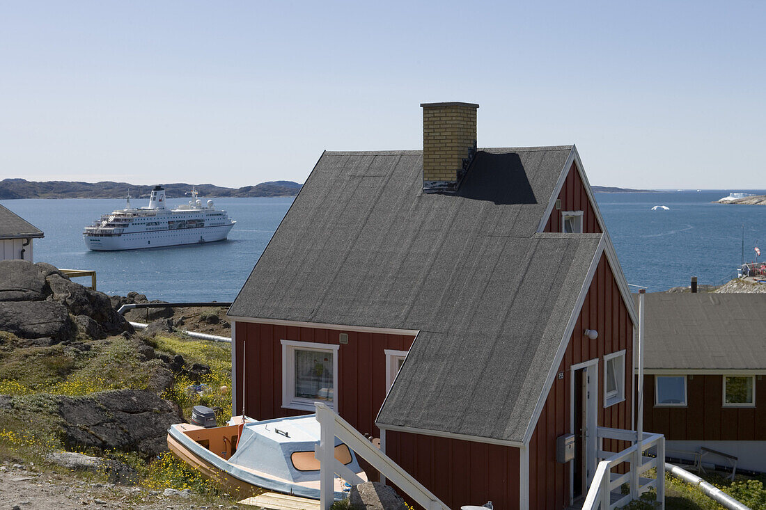 Rotes Holzhaus und Blick auf Kreuzfahrtschiff MS Deutschland, Qaqortoq, Kitaa, Grönland