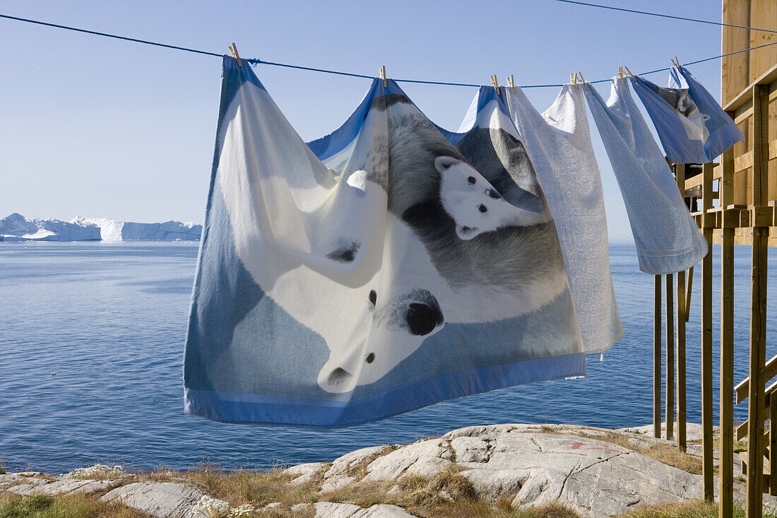 Bed linen hanging on clothes line in front of icebergs of Ilulissat Kangerlua Isfjord, Ilulissat (Jakobshavn), Disko Bay, Kitaa, Greenland