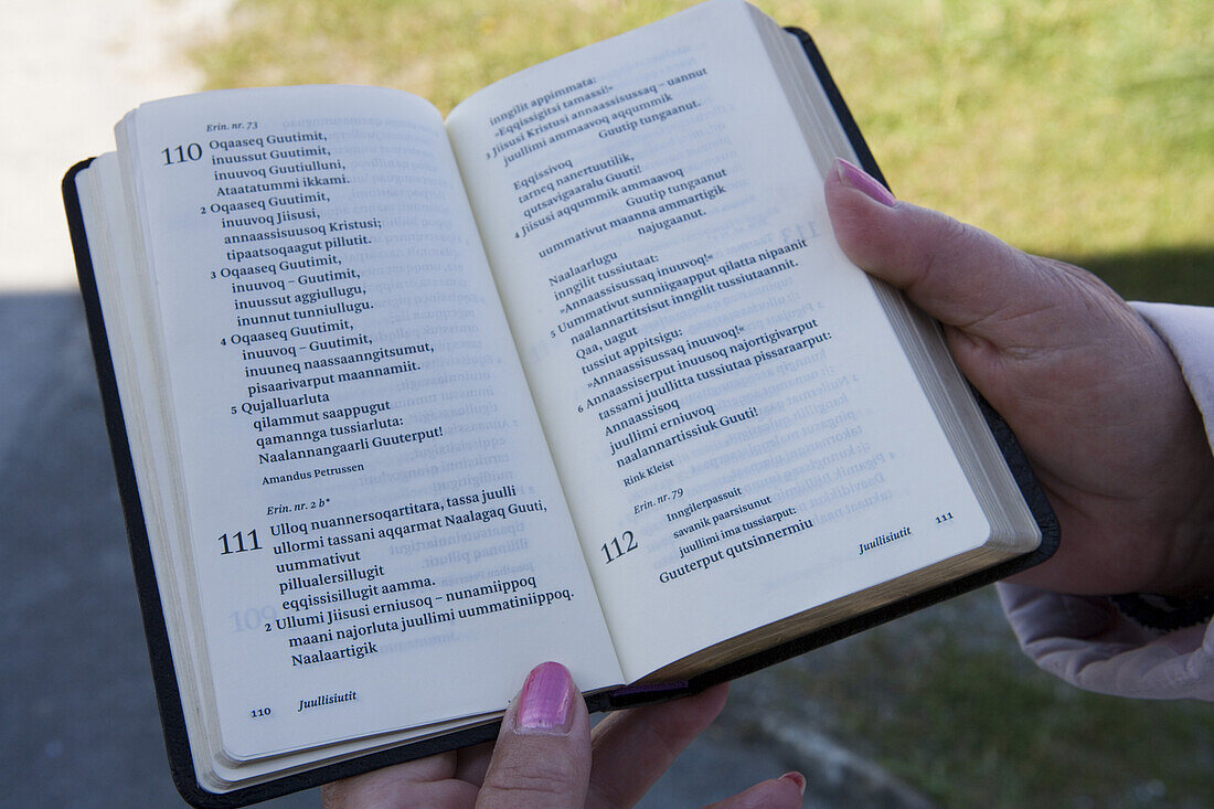 Frau hält Gesangbuch in grönländischer Sprache, Sisimiut, Kitaa, Grönland