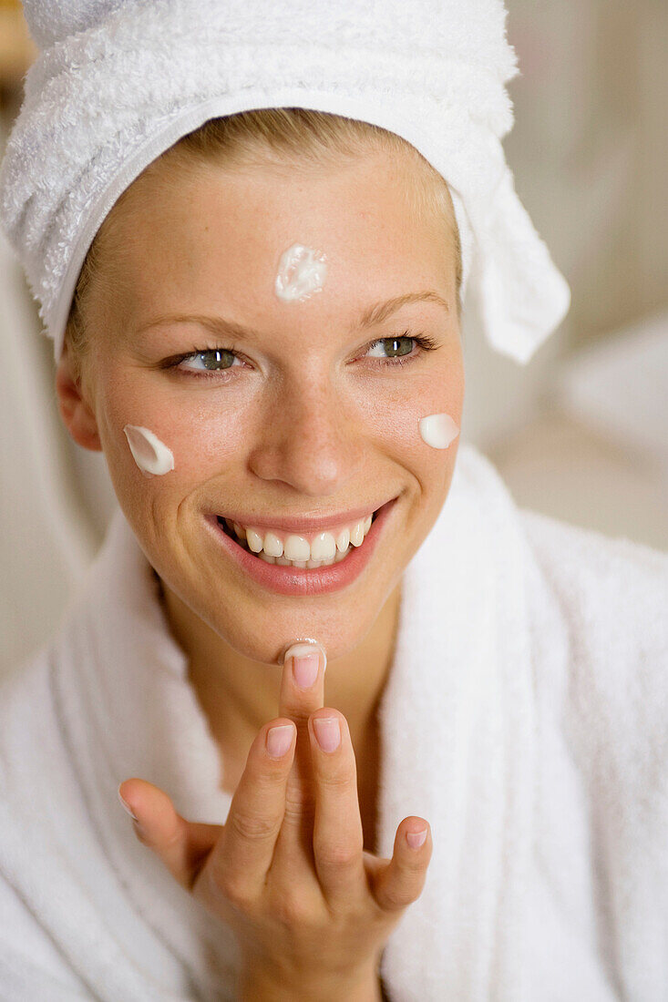 Woman applying moisturazing cream on her face