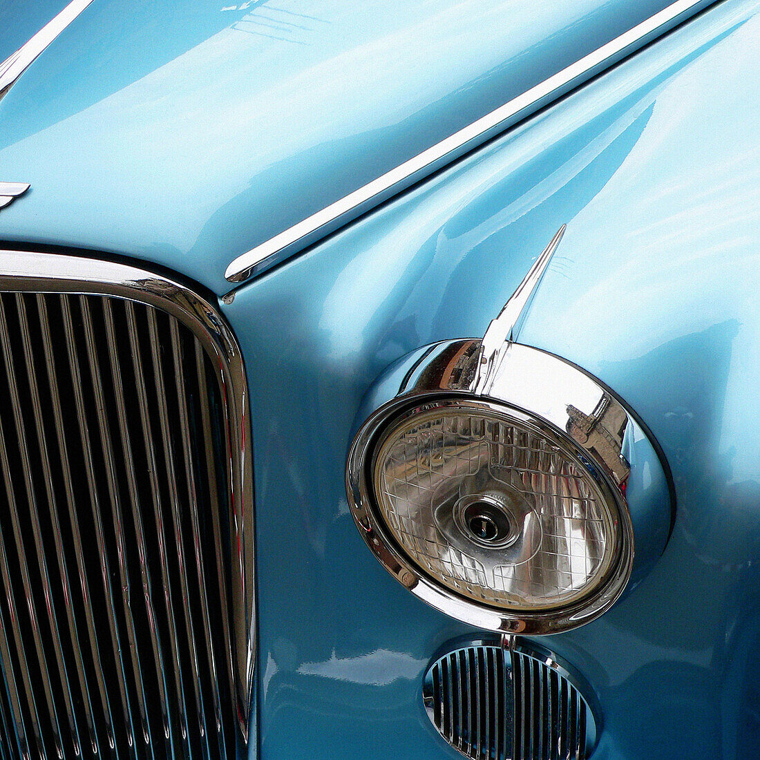 Detalle delantero de un coche de época de color azulen perfecto estado