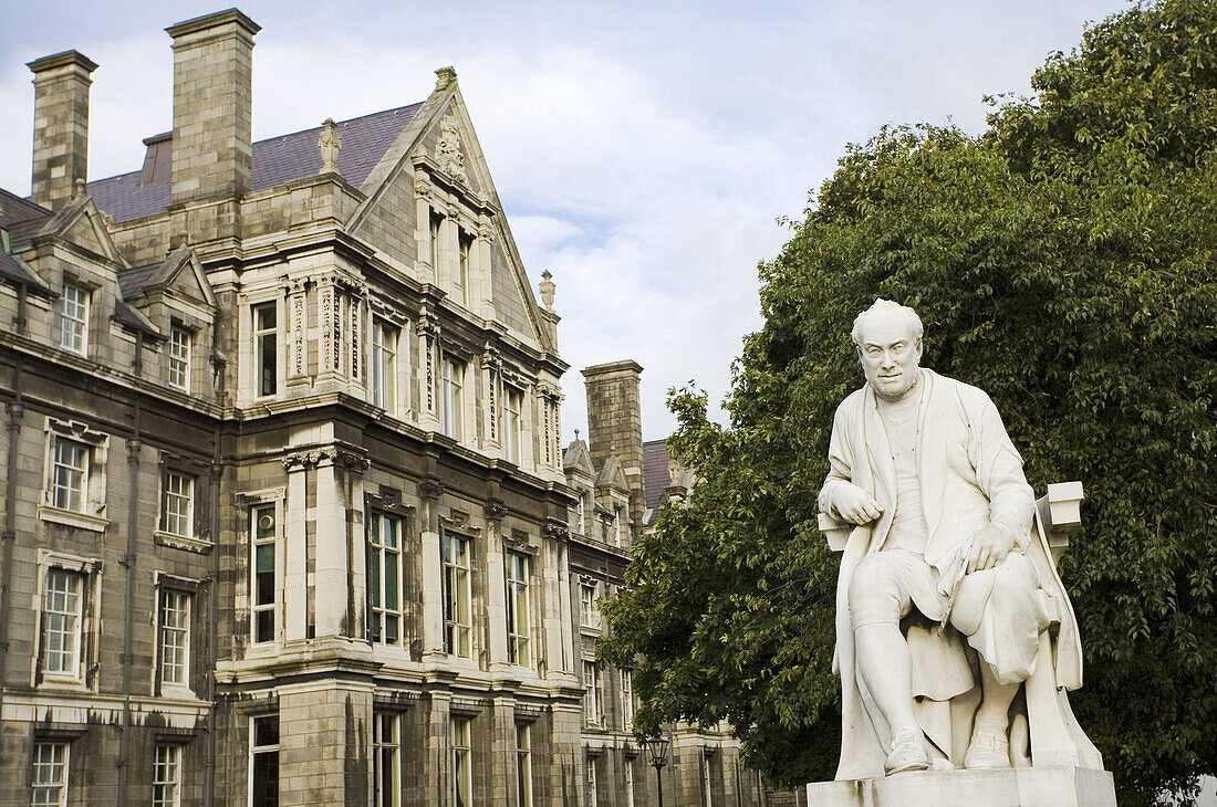 Statue of a man in front of an education building Trinity College, Dublin, Republic Of Ireland