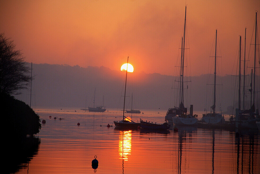 the sun rising over the harbour in kinsale, west cork ireland with the marina and a red skyline