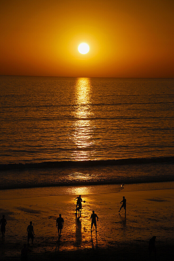 kids playing football on the beach in morrocco and enjoying th last of the sun