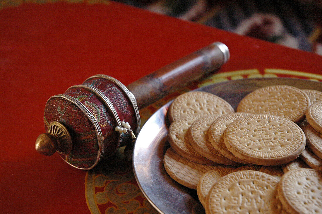 A hand prayer wheel and a plate of cookies on a table Lama Yuru,  Ladakh,  India