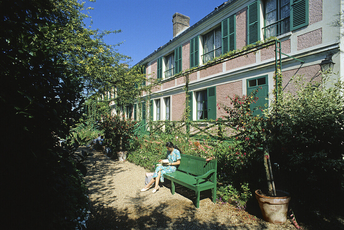 Frau auf einer Bank vor dem Sommerhaus in Monets Garten, Giverny, Normandie, Frankreich, Europa