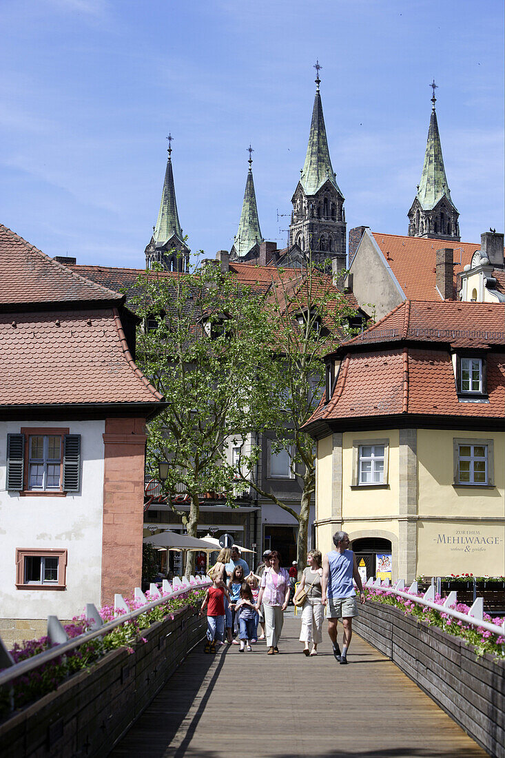 Pedestrians on a bridge overthe Regnitz river and the four steeples of the cathedral, Bamberg, Upper Franconia, Bavaria, Germany