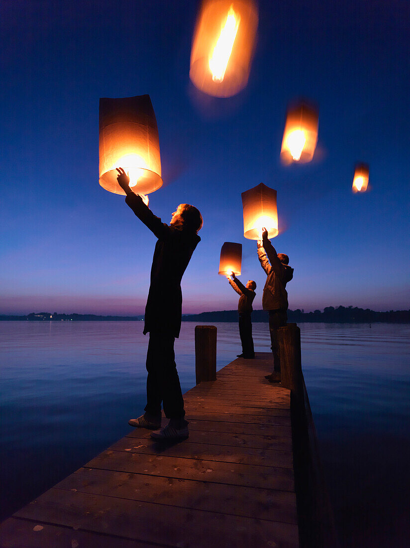 Three persons holding Sky lanterns, Lake … – License image – 70292646 ❘  lookphotos