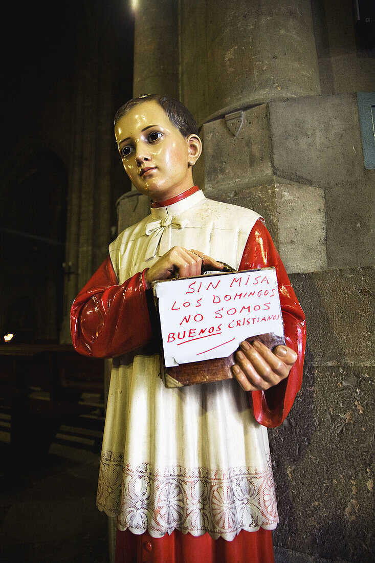 Atalr boy figure holding sign inviting to the Sunday mass at the entrance to Santa Maria de la Antigua church, Valladolid. Castilla-Leon, Spain
