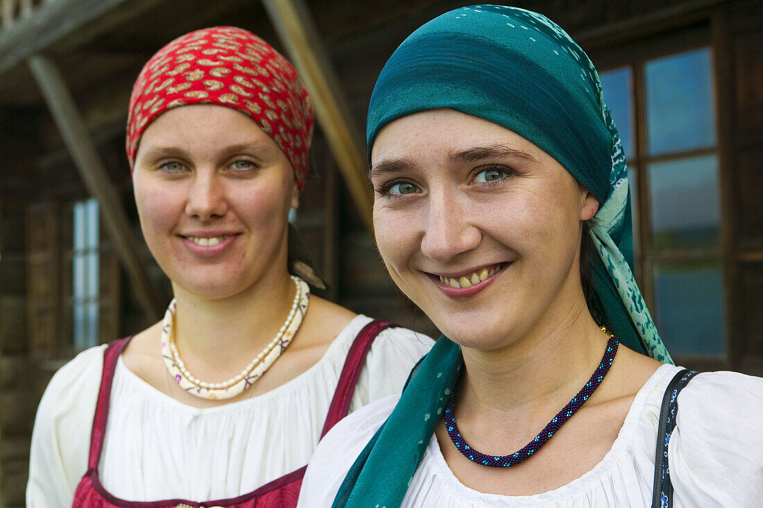 Portrait of two women in traditional costume welcoming the tourists to the museum of Russian wooden architecture of Kizhi, Lake Onega, Republic of Karelia, Russia