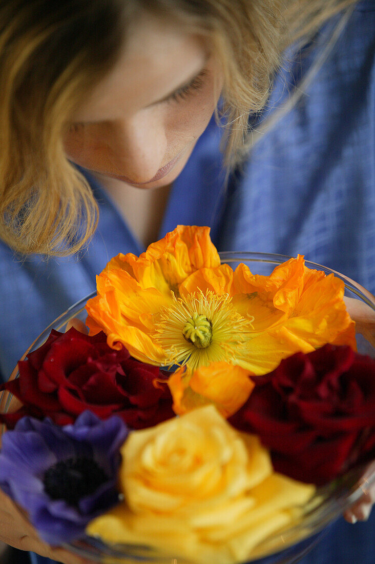 Young woman with colourful flowers in a bowl