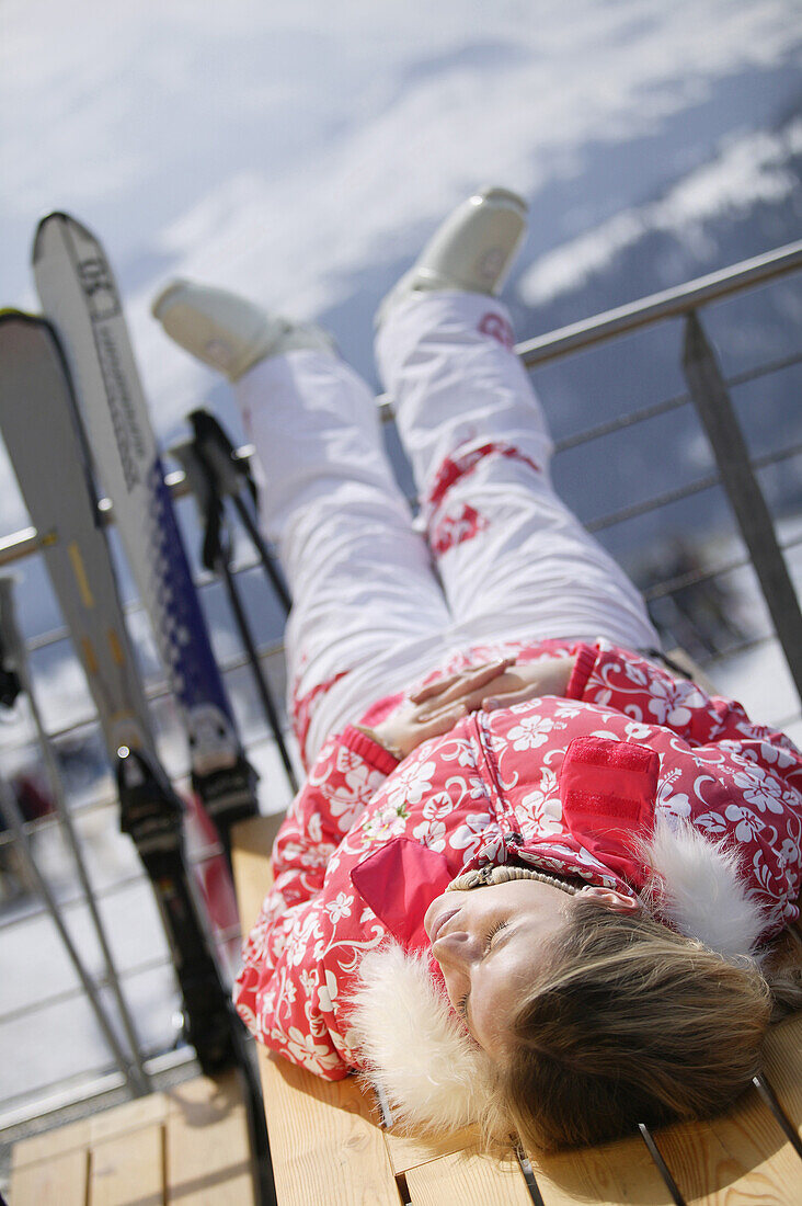 Junge Frau entspannt sich auf der Terasse, Skifahren, Flims, Crap Sogn Gion, Graubünden, Schweiz