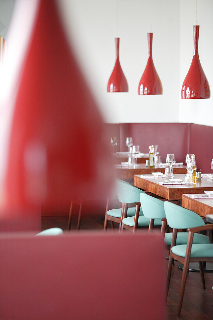Modernes Restaurant, rote Lampen und türkise Stühle