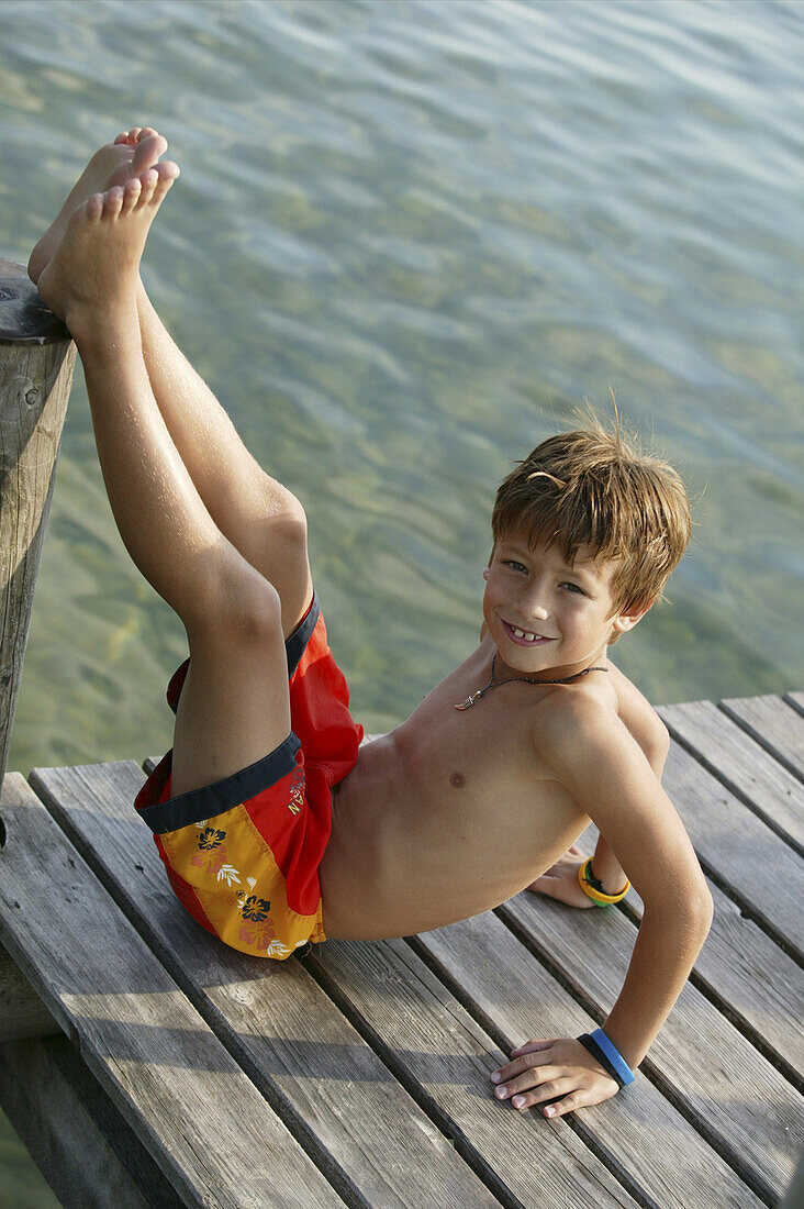 Young boy sitting on pier, Chiemsee, Bavaria, Germany