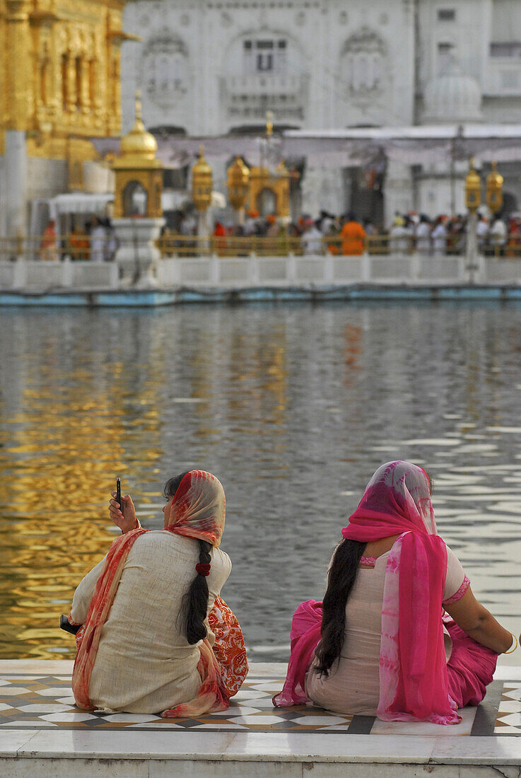Two women in front of the Golden Temple, woman taking pictures with cell phone, Sikh holy place, Amritsar, Punjab, India, Asia