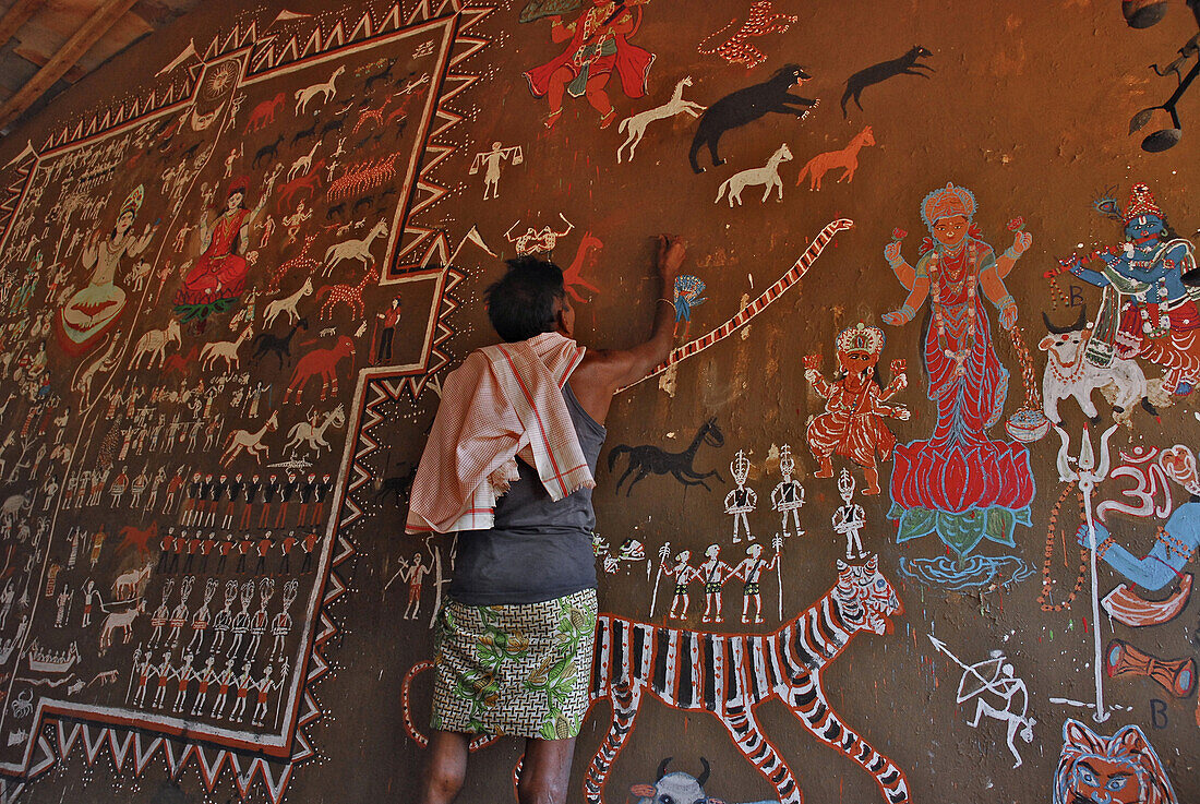 Man painting tribal art on a wall in a ceremonial hall, Bastar, Chhattisgarh, India, Asia