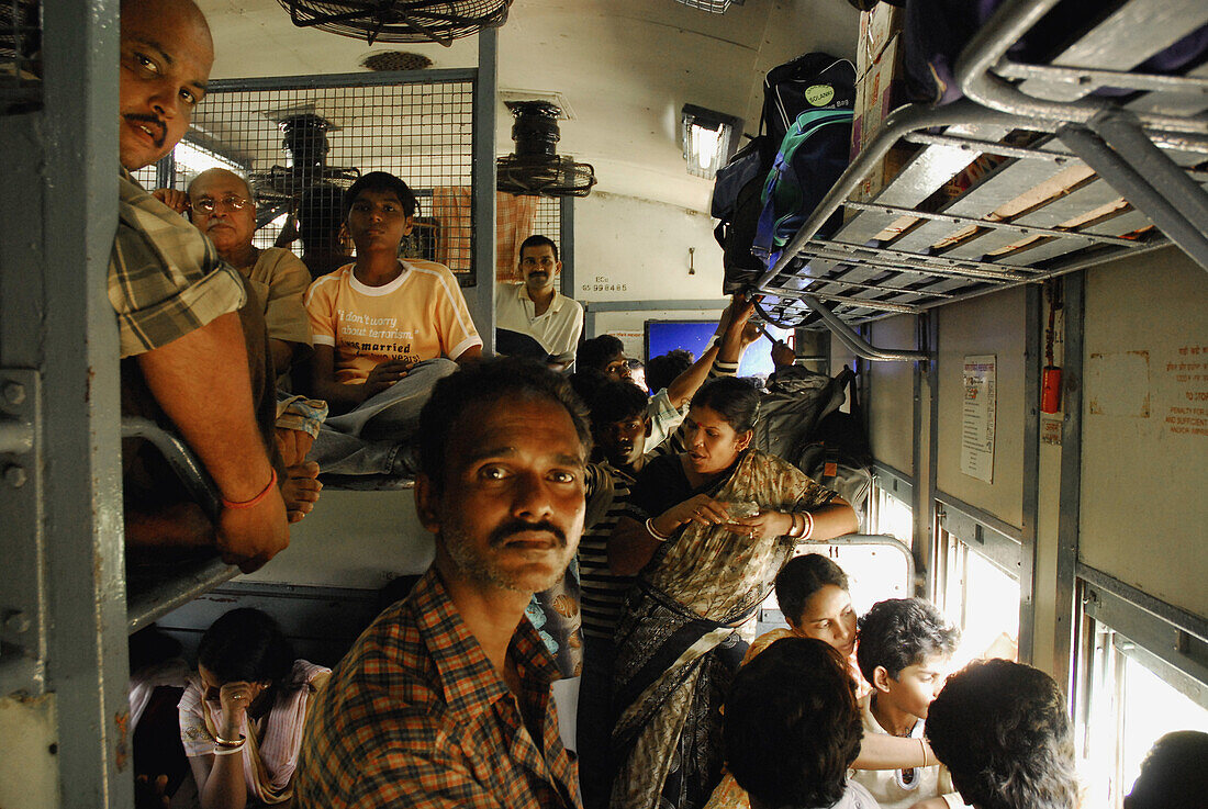 People in a train standing in the aile and sitting on the baggage rack, Orissa, India, Asia