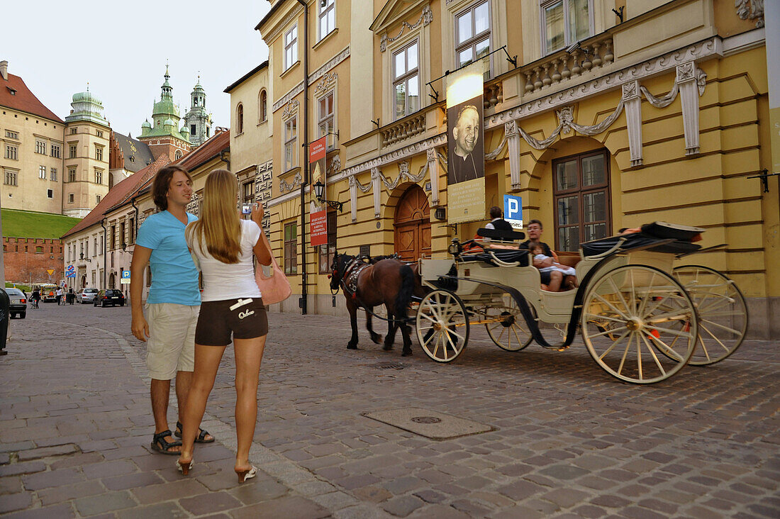 Tourist and horse-drawn carriage at Ulica Kanonicza with Wawel cathedral in the background, Krakow, Poland, Europe