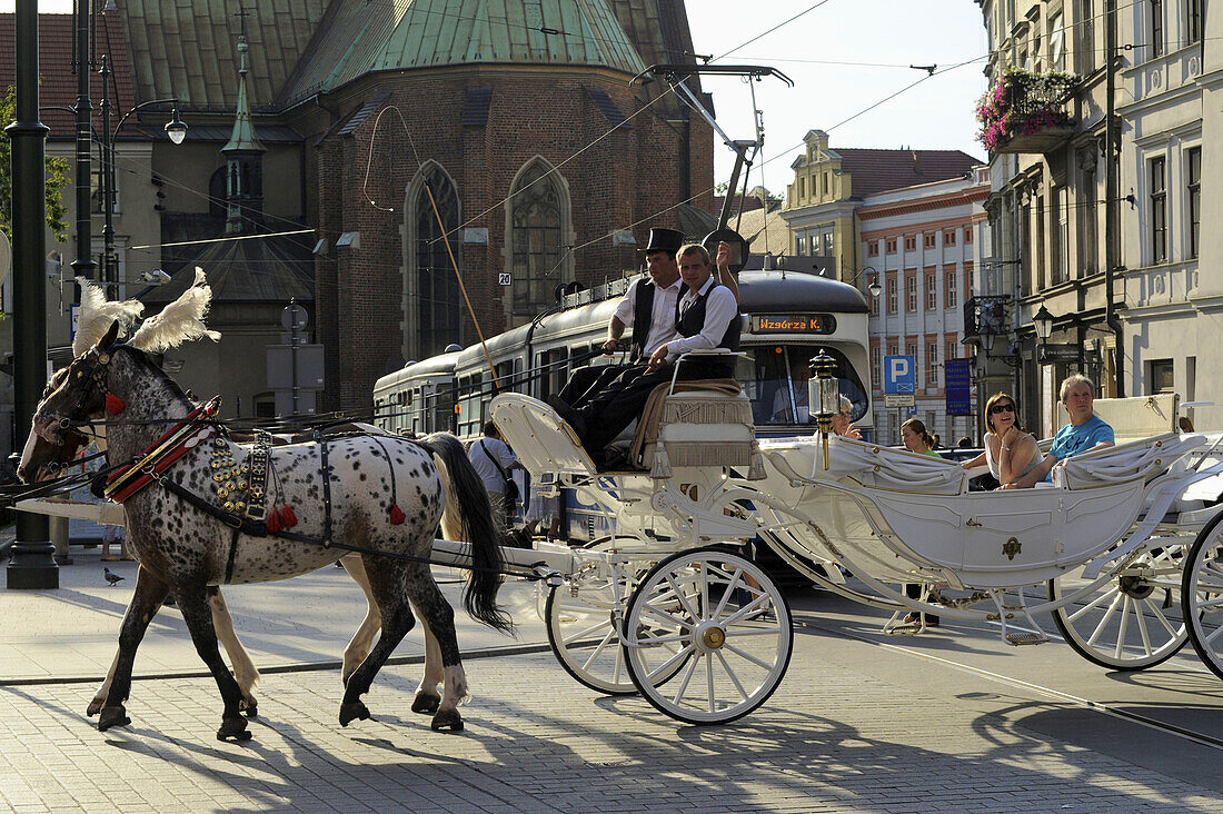 Horse-drawn carriage with tourists in front of tram at ul. Gradzka Ecke Dominikanska, Krakow, Poland, Europe