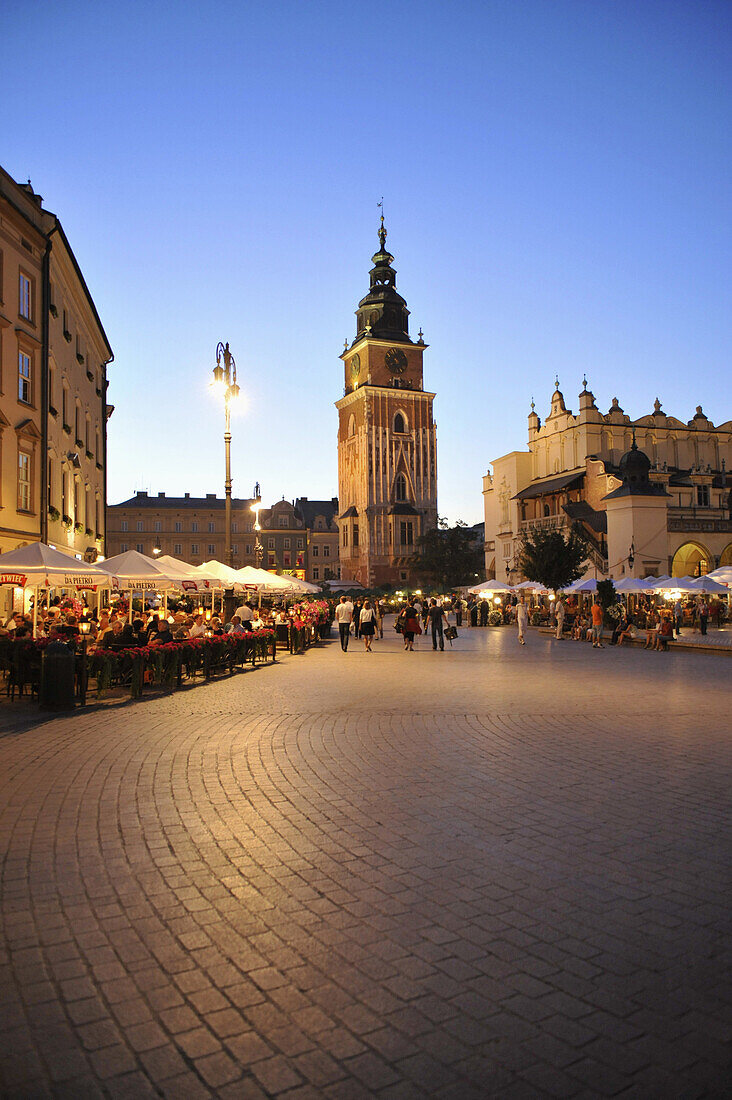 Town hall tower at Rynek glowny, market place with street cafes in the evening, Krakow, Poland, Europe