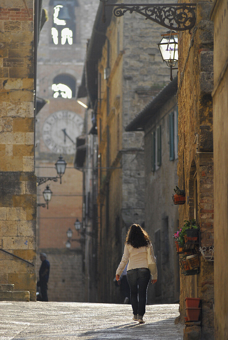 Frau in einer Gasse in der Altstadt mit Blick auf den Kirchturm, Colle di Val d' Elsa, Toskana, Italien, Europa