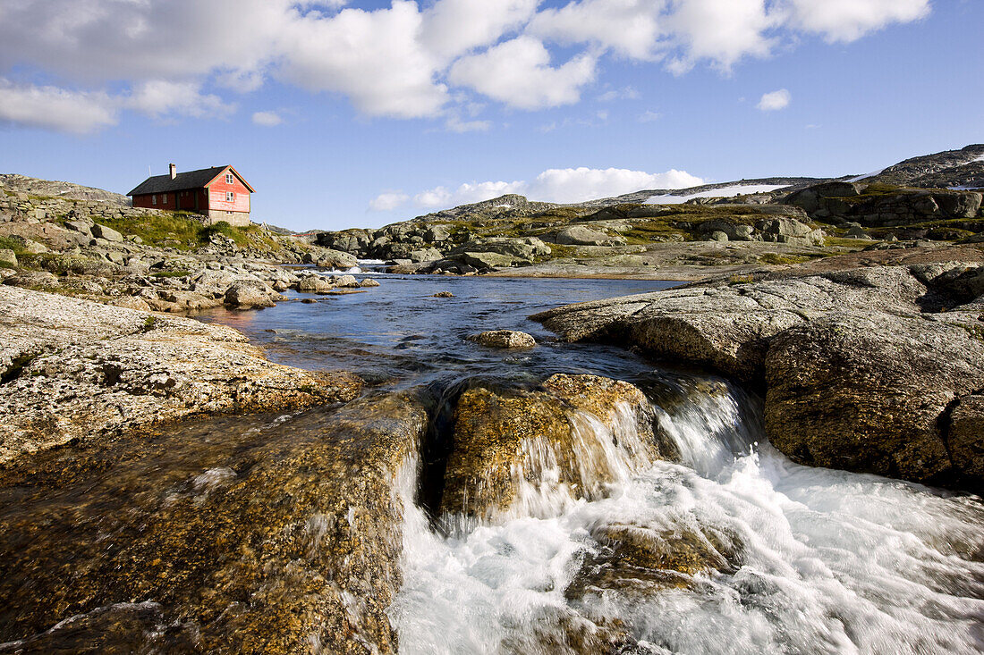 Rotes Holzhaus am Fluß im Nationalpark Hardangervidda, Rallarweg, Hordaland, Südnorwegen, Norwegen, Skandinavien; Spätsommer; Hochebene; Spätsommer; Fjell, Europa