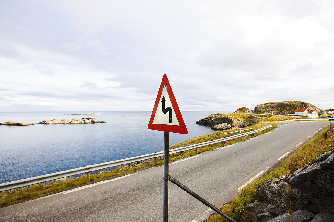 Winding street with warning sign at the coast, Lofoten, Norway, Scandinavia, Europe