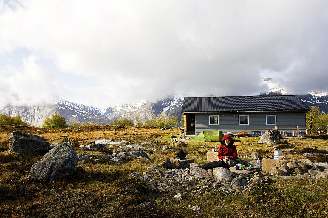 Young woman having breakfast in front of a tent at Folgefonn peninsula, Uskedalen, Hardanger, Norway, Scandinavia, Europe