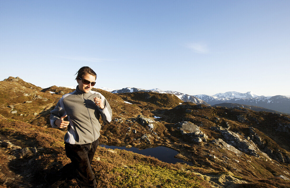 Junge Frau joggt in Fjellandschaft auf dem Malmangersnuten, Folgefonn Halbinsel, Kvinnherad, Hardanger, Hordaland, Norwegen, Skandinavien, Europa