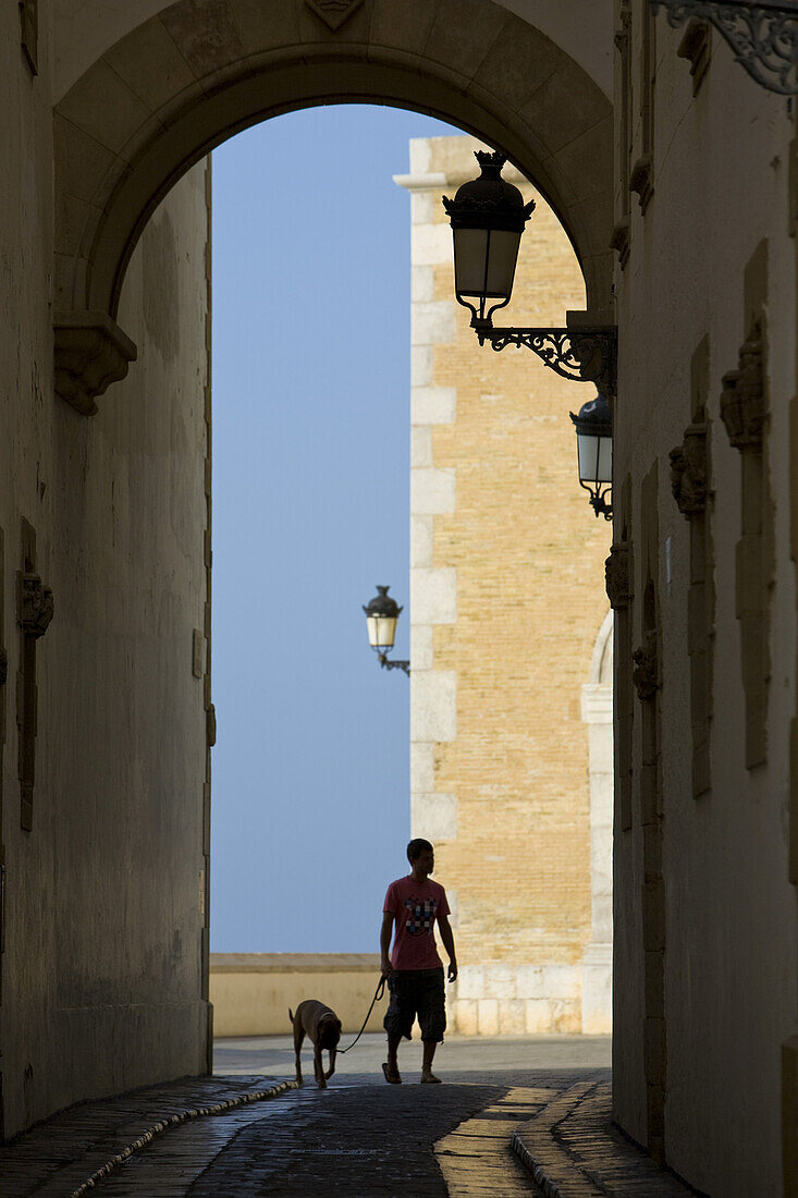 Young man with dog und the archway of Palau Maricel, Maricel de mar, Sitges, Catalonia, Spain, Europe