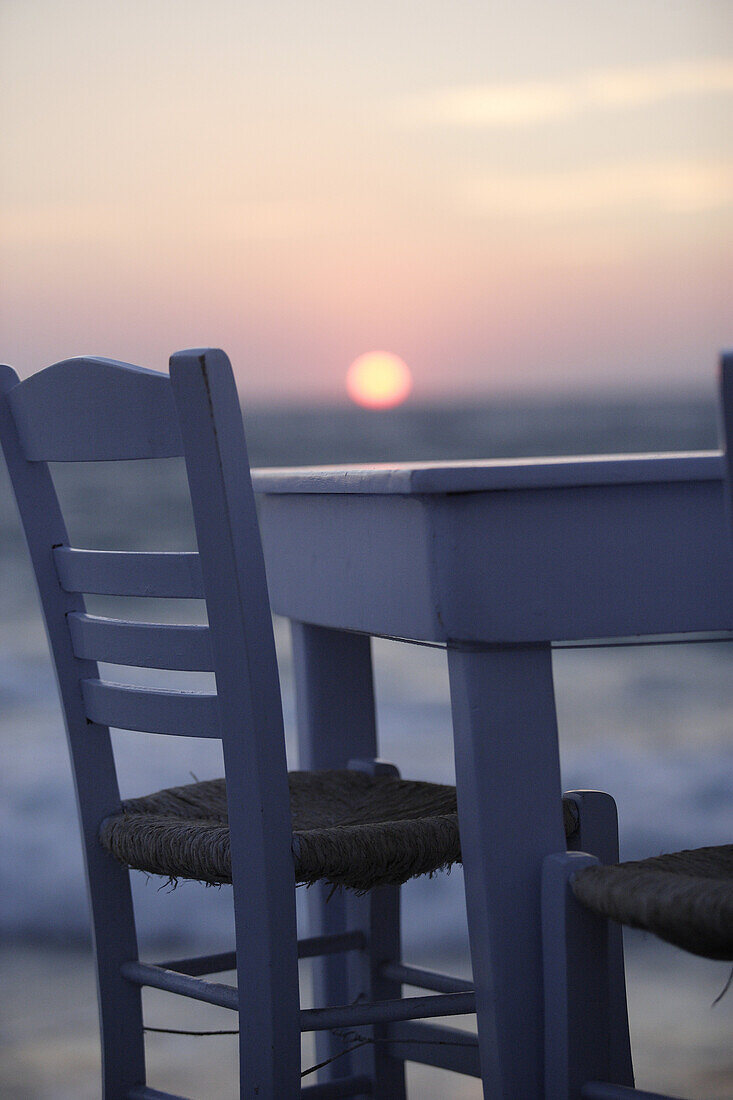 Table and chair at the coast at sunset, Little Venice, Mykonos Town, Greece, Europe