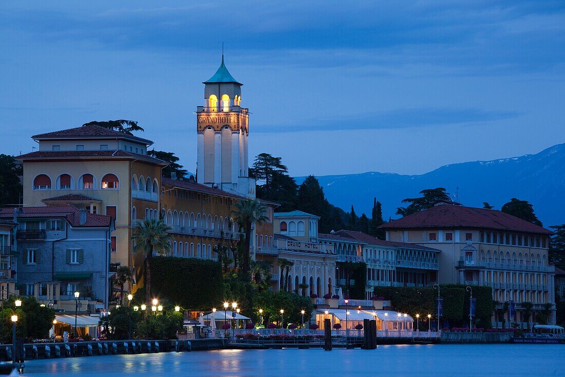 Italy, Lombardy, Lake District, Lake Garda, Gardone Riviera, lakefront town view with Grand Hotel, dusk