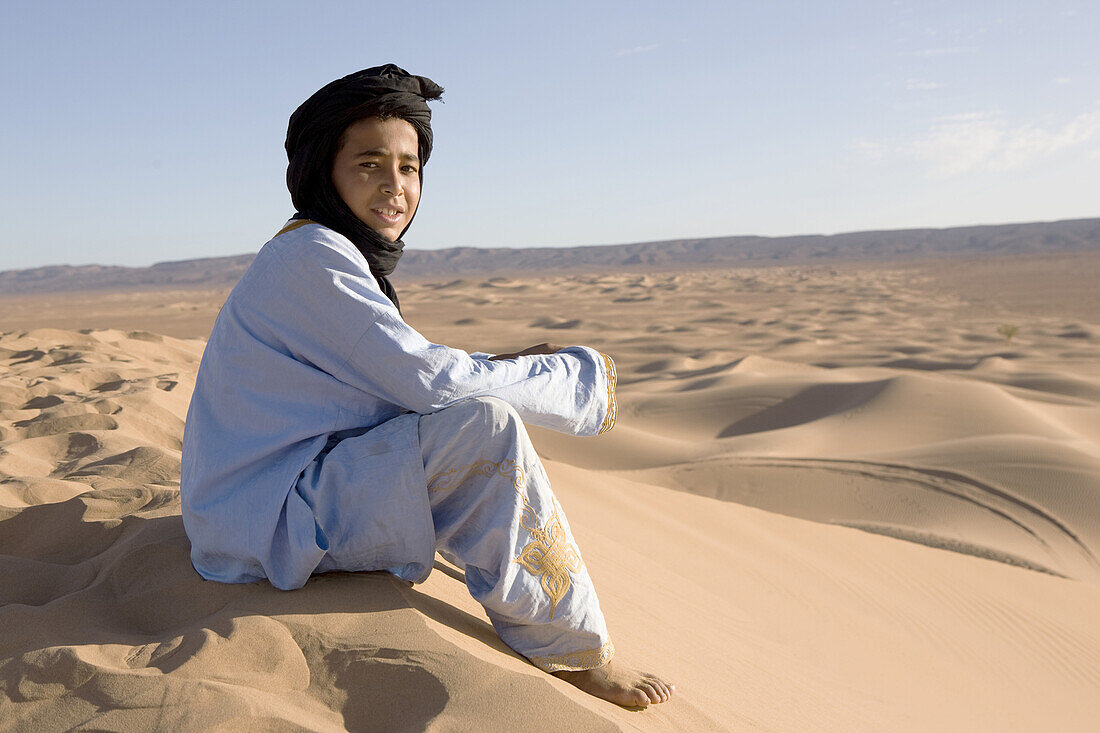 Berber boy in the sand dunes, dunes de Juifs, desert near Zagora, Sahara, Morocco