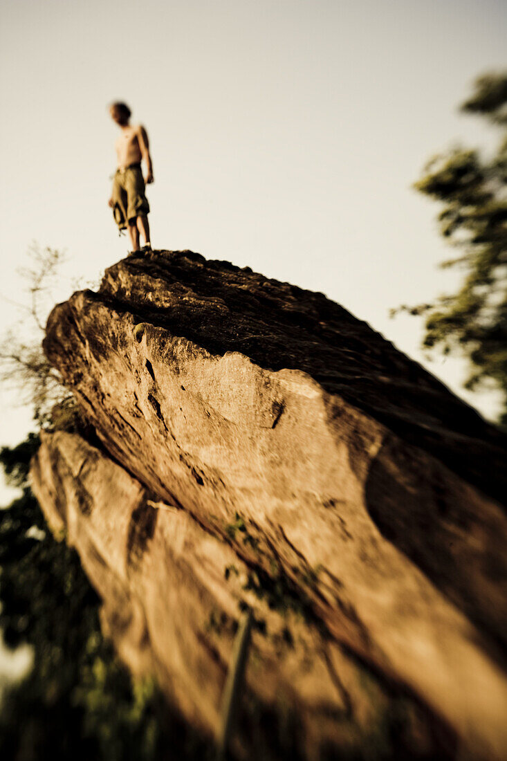 Young man standing on boulder in the morning sun, Mali, Africa